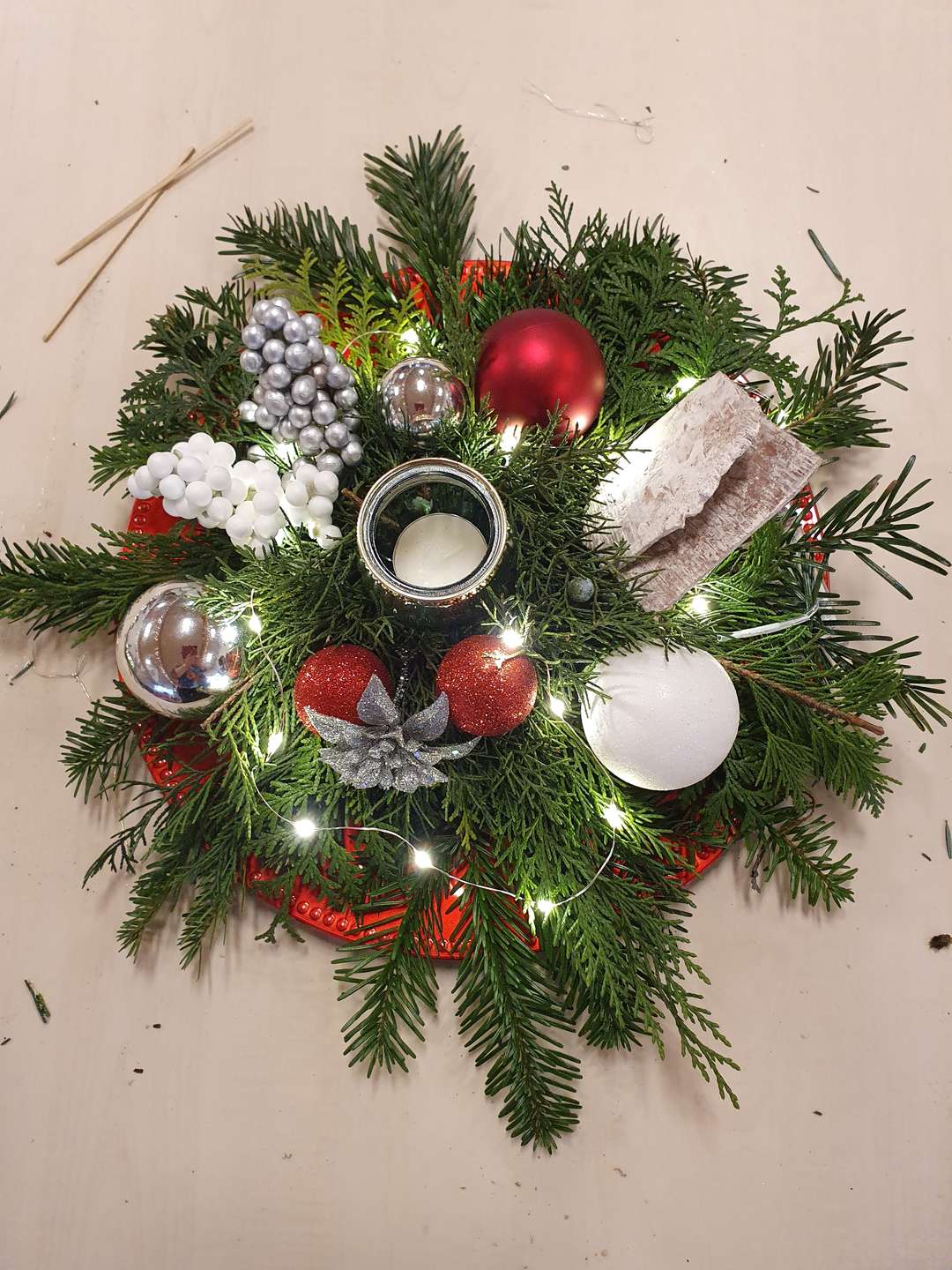 Een foto van een kerststukje, met kerstballen en lichtjes