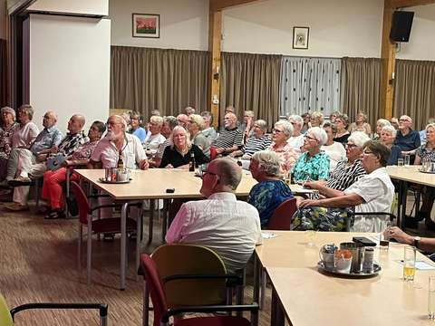 foto van een zaal met aandachtig luisterende mensen