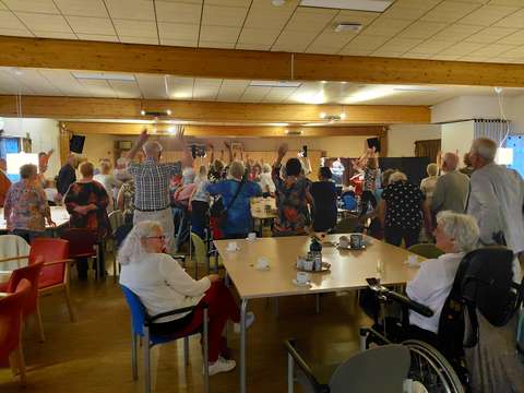 zaal van enthousiaste mensen die genieten van zang van NeighbourSisters