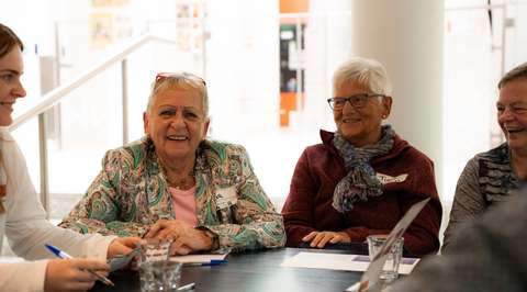 Drie lachende dames aan gesprekstafel | Krachtig ouder worden